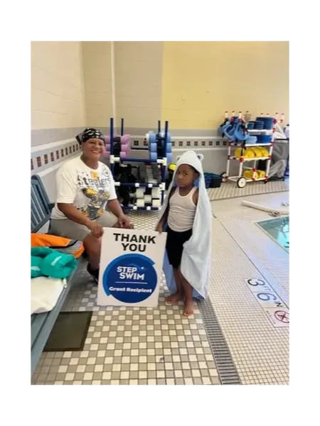 A Step Into Swim grant recipient poolside with a thank-you sign